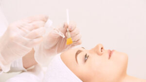 Woman against pink background is pampered before her chemical peel.