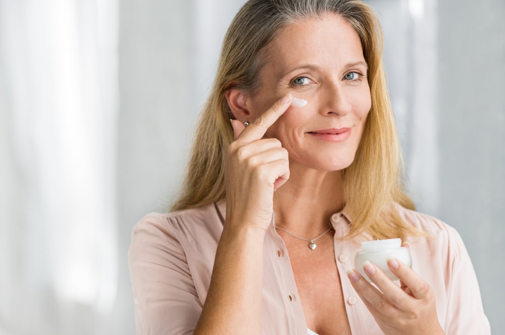 Woman applies cream beneath her eyes to keep her appearance looking young.